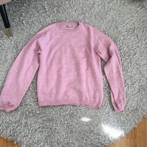 Ljusrosa stickad tröja från only - Supermysig ljusrosa stickad tröja från only med rund halsringning och långa ärmar. Tröjan har en enkel och clean design med ribbade muddar vid ärmslut och nederkant. Perfekt för lager-på-lager och chill dagar.