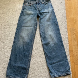 Blå wide jeans från Weekday 26/34 - Säljer ett par blåa Weekday Ample Low Loose jeans i storlek 26/34. De har en loose och wide passform. Jeansen är tillverkade i bomull men har små hål vid bakfickorna 