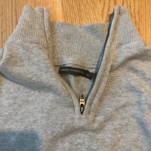 Grå half zip tröja från French Connection - Snygg grå tröja från French Connection med half zip och hög krage. Tröjan har långärmade ribbade muddar och är tillverkad i mjuk bomull. Perfekt för dig som gillar stilrena och enkla plagg med en modern touch.