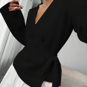 Svart omlott kofta med knytband - Pris kan diskuteras❤️ Snygg svart omlott kofta med knytband i midjan och v-ringad hals. Koftan har långa ärmar och är gjord i ett stickat material som känns både mjukt och stilrent. Perfekt för lager-på-lager och passar till många olika outfits.