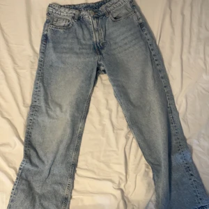 Ljusblå raka jeans i storlek 164 - Ljusblå jeans med klassisk femficksdesign och raka ben. Jeansen har normalhög midja och stängs med dragkedja och knapp. Perfekta för en avslappnad och stilren look. Materialet är slitstark denim i bomull.
