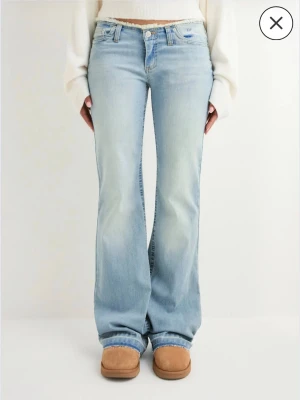 Ljusblå bootcut jeans med rå kant - Säljer ett par ljusblå jeans med bootcut passform och låg midja. Jeansen har en snygg rå kant upptill och klassiska fem fickor. Materialet är mjukt denim i bomull! Säljer för att jag aldrig använder ljusa jeans, och har endast provat dom🥳