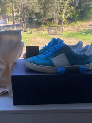 Valentino flycrew - Säljer ett par Valentino Rockrunner sneakers i blå mocka med vita detaljer och matchande blå skosnören.  platt sula med coolt kamouflagemönster undertill. Kommer med extra skosnören och dustbag. Sulan på vänster fot är limmat av sneakers tvätten som är professionella annars är det inget fel på dem.