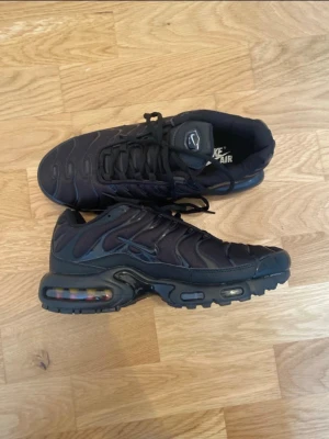 Svarta Nike Air Max sneakers - Säljer ett par svarta Nike Air Max sneakers med klassisk luftsula och snygga detaljer på ovandelen. Skorna har snörning och en chunky sula som ger grym streetstil. Perfekta för dig som gillar sportig look och vill ha bekväma skor till vardags.