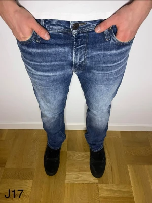 Blå jeans från Jack & Jones - Snygga blå jeans från Jack & Jones med klassisk femficksdesign och tydliga slitningar framtill. Jeansen har normal passform och raka ben, tillverkade i mjukt bomullsmaterial för skön känsla. Perfekta för en avslappnad och trendig look.