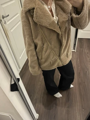 Beige teddyjacka med dragkedja - Mysig beige teddyjacka med stor krage och sned dragkedja framtill. Jackan har långa ärmar, fickor med dragkedja och en oversized passform. 