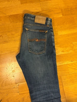 Mörk Blå slim jeans från Nudie Jeans - Ett par feta Nudie Jeans som är slim fit. Det finns ett litet hål på vänstra benet men man vi märker inte det.