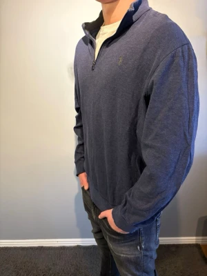 Ralph Lauren - Mörkblå långärmad tröja från Polo Ralph Lauren med quarter zip och liten broderad logga på bröstet. Perfekt för en avslappnad men stilren look. Storlek xl men passar mer som L. Modellen är 184cm