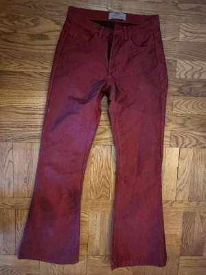 Bootcut vinröda jeans - Snygga vinröda bootcut jeans med klassisk femficksdesign. Jeansen har en något utsvängd passform nertill och är tillverkade i ett jeanstyg som känns både slitstarkt och bekvämt. Perfekta för dig som vill sticka ut med färg och form.