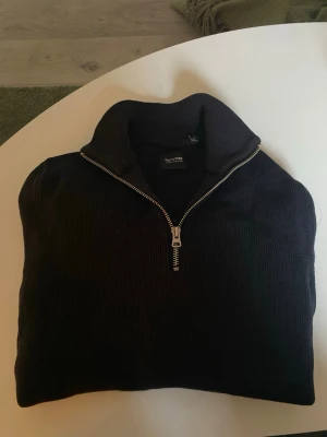 Svart stickad tröja med halvzip - Snygg svart stickad tröja från Only & Sons med halvzip och hög krage. Tröjan har ribbad struktur och långa ärmar, perfekt för lager på lager. Passar till både jeans och kjol för en chill look.