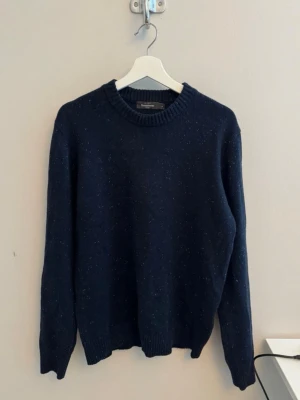 Stickad ulltröja - Säljer en mörkblå stickad ulltröja från Dressman i Storlek M. Tröjan är i nyskick och använd endast ett fåtal gången. Köpt i november 2025 för 700 kr. Kvitto medföljer.