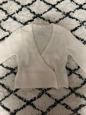 Krämvit omlottkofta😍🌟 - Snygg krämvit stickad omlottkofta från gina med djup V-ringning och knäppning med fyra knappar i sidan. Koftan har långa ärmar och bred ribbstickad kant nedtill och vid ärmsluten. Perfekt för lager-på-lager-stil. Det är storlek 158/164 men har råkat dra av lappen ( liten i modellen)