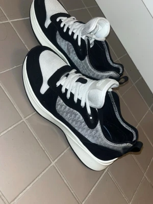 Svarta och vita sneakers  - Säljer ett par snygga  sneakers i svart och vitt med vita snören och tjock sula. Ovandelen har meshdetaljer och mockaliknande partier för en modern look. Perfekta för dig som vill ha en stilren och trendig sko till vardagsoutfiten.