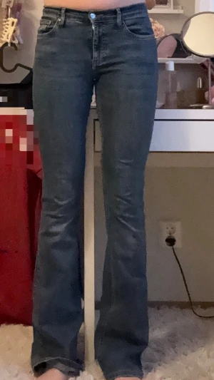 Blå bootcut jeans med medelhög midja - Säljer ett par klassiska blå bootcut jeans med medelhög midja. Jeansen har en tidlös tvätt och utsvängda ben som ger en snygg siluett. Perfekta att styla med sneakers eller boots för en chill look.