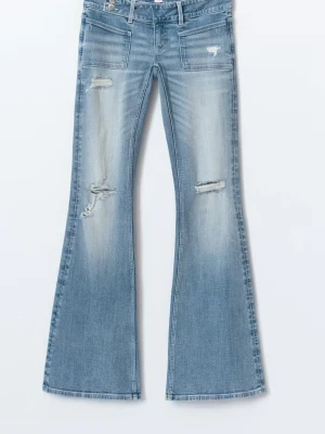 Bootcut ljusblå jeans med slitningar - Säljer ett par ljusblå bootcut jeans med slitningar på låren och knäna. Jeansen har klassisk femficksdesign och är tillverkade i mjukt denimtyg. Perfekta för dig som gillar en avslappnad och trendig look.