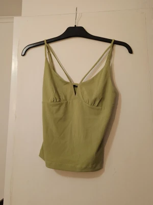 Ljusgrön linnetopp med smala band - Snygg ljusgrön linnetopp med tunna axelband och v-ringad skärning. Toppen har en enkel och stilren design som passar perfekt till jeans eller kjol. Materialet känns mjukt och bekvämt mot huden. 