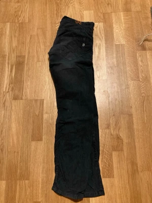 Svarta manchesterbyxor från Dondup - Svarta manchesterbyxor från Dondup med klassisk femficksdesign och diskret D-logga på bakfickan. Byxorna har raka ben och är tillverkade i mjuk manchester som ger en snygg och avslappnad look.