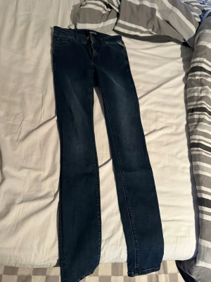 Mörkblå raka jeans från Replay - Snygga mörkblå jeans från Replay med raka ben och klassisk femficksdesign. Jeansen har en diskret Replay-logga på bakfickan och är tillverkade i slitstarkt denimtyg. Perfekta för en clean och tidlös look.