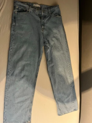Jack and jones ljusblå raka jeans Baggy 31/32 - Klassiska ljusblå Jack N Jones jeans med rak passform och fem fickor. Jeansen har knappgylf och är tillverkade i 100% bomull för en autentisk denimkänsla. Perfekta för en avslappnad och tidlös stil.
