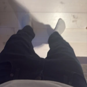 Svarta Lee jeans herr - Säljer ett par svarta Lee jeans med klassisk femficksdesign och knappgylf. är tillverkade i mjukt bomullsmaterial med lite stretch för extra komfort. Perfekta för dig som gillar en stilren och enkel look.