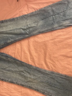 Blå jeans med stora fickor fram - Säljer ett par ljusblå jeans med raka ben och stora fickor framtill. Jeansen har låg midja och klassisk knappgylf. Perfekta för en avslappnad och trendig look. Materialet är mjukt denim i bomull.