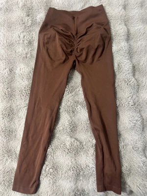 Bruna scrunch träningsleggings  - Bruna leggings med scrunch-detalj bak och hög midja. Använda endast 1 gång. 