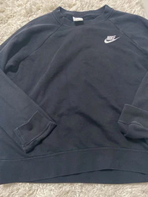 Mörkgrå stickad sweatshirt från Nike - Säljer en svart sweatshirt från Nike med klassisk vit logga broderad på bröstet. Tröjan har rund halsringning, långa ärmar och ribbade muddar vid ärmslut och nederkant. Perfekt för en avslappnad och sportig look. Priset kan diskuteras 