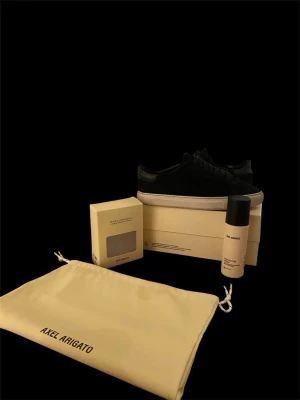Svarta sneakers från Axel Arigato - Stilrena svarta sneakers från Axel Arigato . Skorna har snörning och är tillverkade i mocka. Medföljer originalpåse, och en protector spray. Köpt för 3000kr och priset går att diskuteras. Passar 40, 41 och oftast 42