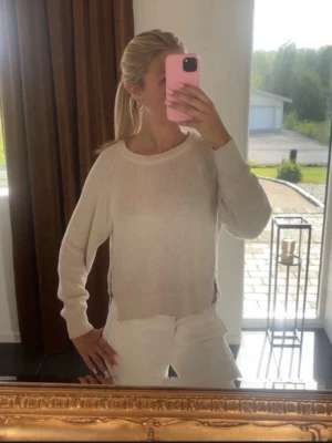 Beige stickad tröja med dragkedjor - Beige stickad tröja med rund halsringning och långa ärmar. Tröjan har ribbstickade muddar och dragkedjor i sidorna som en snygg detalj. Perfekt att styla med jeans eller kjol för en avslappnad look.