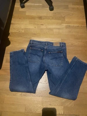 Nudie Jeans - Klassiska blåa nudie med rak passform och femficksmodell. Jeansen har normal midja och är tillverkade i slitstarkt bomullsdenim. Perfekta för en avslappnad och tidlös stil. Storlek 32/32 pris kan diskuteras