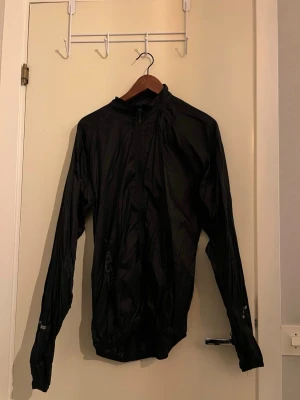 Svart vindjacka från 157.FUNK - Säljer en svart vindjacka från 157.FUNK i storlek medium. Jackan är tillverkad i tunn nylon, har lång ärm och dragkedja framtill. Perfekt för blåsiga dagar och enkel att packa ner i väskan. Minimalistisk design utan synliga loggor på utsidan.