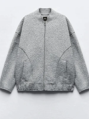 Grå teddy bomberjacka från Zara - Säljer en grå teddy bomberjacka från Zara med dragkedja framtill och två fickor. Jackan har en oversized passform och är tillverkad i mjukt teddy-material som ger en mysig vibe. Fick precis hem den men var för stor därför säljer jag den. 