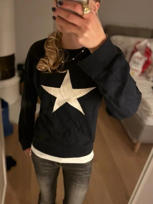 Svart tröja med vit stjärna - Cool svart tröja med stor vit stjärna på. Tröjan har rund halsringning och långa ärmar, perfekt för en avslappnad och trendig look. Passar till både jeans och kjol för en snygg vardagsstil. Pris kan diskuteras 💕💕