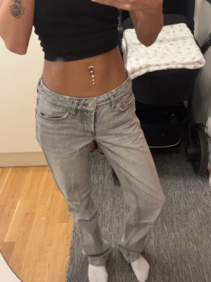 Ljusgrå raka jeans - Säljer ett par ljusgrå jeans med rak passform och klassisk femficksdesign. Jeansen har låg midja och är tillverkade i ett mjukt denimtyg som ger en avslappnad vibe. Perfekta till en crop top eller hoodie.