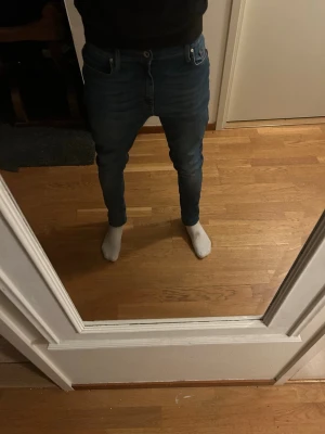 Blå skinny jeans i stretch från tiger of Sweden  - Säljer ett par blå skinny jeans med smal passform och klassisk femficksdesign. Jeansen har en lätt tvättad look och är tillverkade i stretchigt denimtyg för extra komfort. Perfekta till vardags och matchar enkelt med olika stilar.