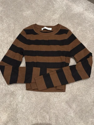 Brun och svart randig tröja - Nästan aldrig använt då jag inte tycker det är min stil. Snygg croppad långärmad tröja från Zara med breda bruna och svarta ränder. Tröjan har rund halsringning och är figurnära i modellen.