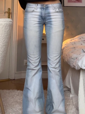 Ljusblå bootcut jeans med utsvängda ben - Säljer ett par ljusblå bootcut jeans från ping med  utsvängda ben. Jeansen har en snygg cool tvätt. Första bilden beskriver bäst färgen då den är i dagsljus. Jeansen har slitningar vid fötter och ett väldigt litet hål på ena knäet. Men det är ingenting man tänker på. Annars känns jeansen som nya. Passar xs-s