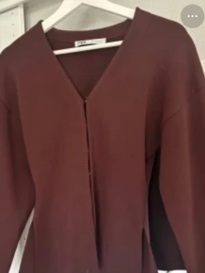 kofta med v-ringning från zara  - Snygg kofta från zara med djup v-ringning och knappar framtill. Modellen är figurnära med långa ärmar och lätt stretchigt material. Perfekt att styla med jeans eller kjol för en trendig look.