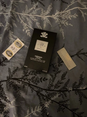 Creed Aventus Eau de Parfum 100ml - Creed Aventus Eau de Parfum i 100 ml flaska. Flaskan är genomskinlig med svart etikett och silverdetaljer, samt svart kork. Kommer med originalförpackning och tillhörande kort. En ikonisk doft med lyxig känsla.