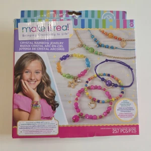 Make It Real Crystal Rainbow armband-kit - Gör egna färgglada armband med Make It Real Crystal Rainbow Jewelry kit! Innehåller pärlor i regnbågens färger, guldiga detaljer och berlocker samt elastiska trådar. Perfekt för dig som vill skapa unika smycken med glittriga och färgstarka pärlor. Förpackningen är öppnad men inte små påsarna. 