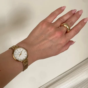 Mockberg guld klocka med mesharmband - Snygg och stilren klocka från Mockberg med rund vit urtavla och guldiga detaljer. Klockan har ett elegant mesharmband i guld och minimalistisk design utan siffror. Perfekt accessoar för dig som gillar klassisk och modern stil.