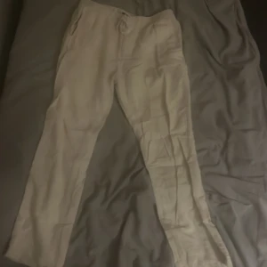 Beiga linnebyxor med dragsko - Snygga beiga linnebyxor med avslappnad passform och dragsko i midjan. Perfekta för varma dagar och ger en chill vibe. Byxorna har fickor på sidorna och är tillverkade i ett lätt och luftigt linnematerial.