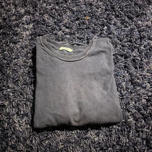 Svart tröja från J.Lindeberg - En stilren svart tröja från J.Lindeberg i storlek L. Tröjan har rund halsringning och är tillverkad i mjukt material som passar perfekt till lager-på-lager. Enkel och clean design som funkar till många olika looks.