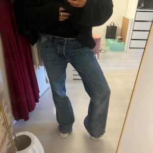 Blåa wide jeans med råa kanter - Säljer ett par blåa jeans med breda ben och råa, fransiga kanter nertill. Klassisk femficksmodell i jeansmaterial med normal passform och midja. Perfekta för en avslappnad och trendig look.