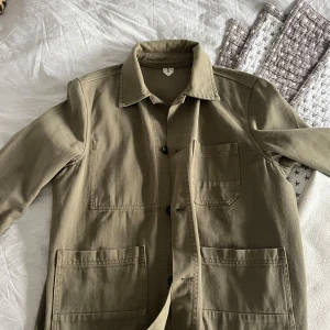 Steker overshirt  - Snygg mörkgrön overshirt med klassisk krage och tre stora fickor framtill. Jackan är tillverkad i slitstark bomull och har knäppning med svarta knappar. Perfekt att slänga över en hoodie eller t-shirt för en chill look.