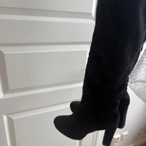 Svarta höga stövlar med klack - Säljer ett par svarta höga stövlar med chunky klack och rund tå från about you. Skorna är i mocka-liknande material och har en stilren, minimalistisk design som passar perfekt till höst och vinter. Supersnygga till både jeans och kjol! Nypris 799kr.