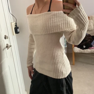 Offshoulder ribbad stickad tröja Lindex - Superfin offshoulder stickad tröja från Lindex i beige. Tröjan är ribbstickad med lång ärm och sitter snyggt figurnära. Perfekt för dig som gillar en stilren och trendig look med lite extra edge.
