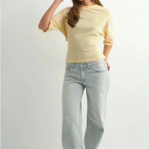 Gul omlottopp med knyt i ryggen - Snygg ljusgul omlottopp med korta ärmar och knyt i ryggen som ger en öppen rygg. Toppen har en croppad passform och är tillverkad i mjuk bomull. Perfekt för dig som gillar trendiga detaljer och vill sticka ut med en cool look.