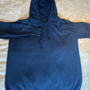 Mörkblå kashmire hoodie - Snygg mörkblå hoodie med klassisk huva och snörning framtill. Tröjan har långa ärmar med ribbade muddar och är tillverkad i ett mjukt stickat material. Perfekt för chill dagar och enkel att matcha med jeans eller joggers.