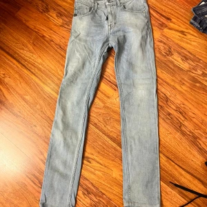 Ljusblå skinny jeans från T/J - Säljer ett par ljusblå skinny jeans från T/J med klassisk femficksdesign och snygga slitningar. Jeansen har smal passform och är tillverkade i mjuk bomullsdenim med lite stretch för extra komfort. Perfekta för en avslappnad och trendig look.